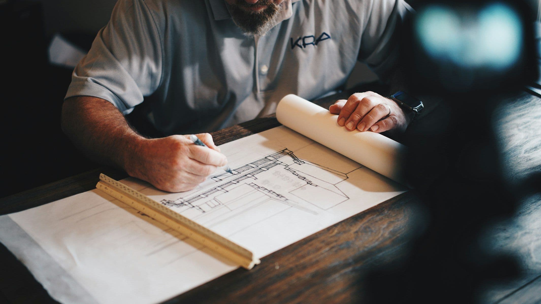 Architectural blueprints, measuring tools and a calculator laid out on a desk